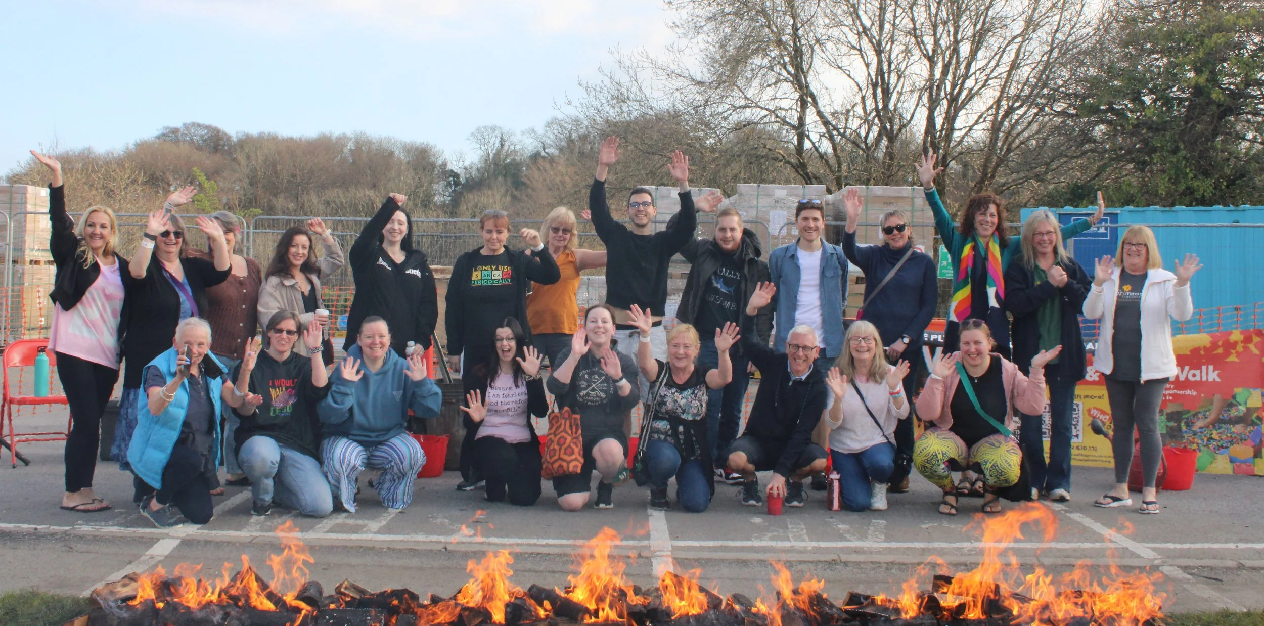 Group photo of the fundraisers raising their hands in the air in front of fiery path