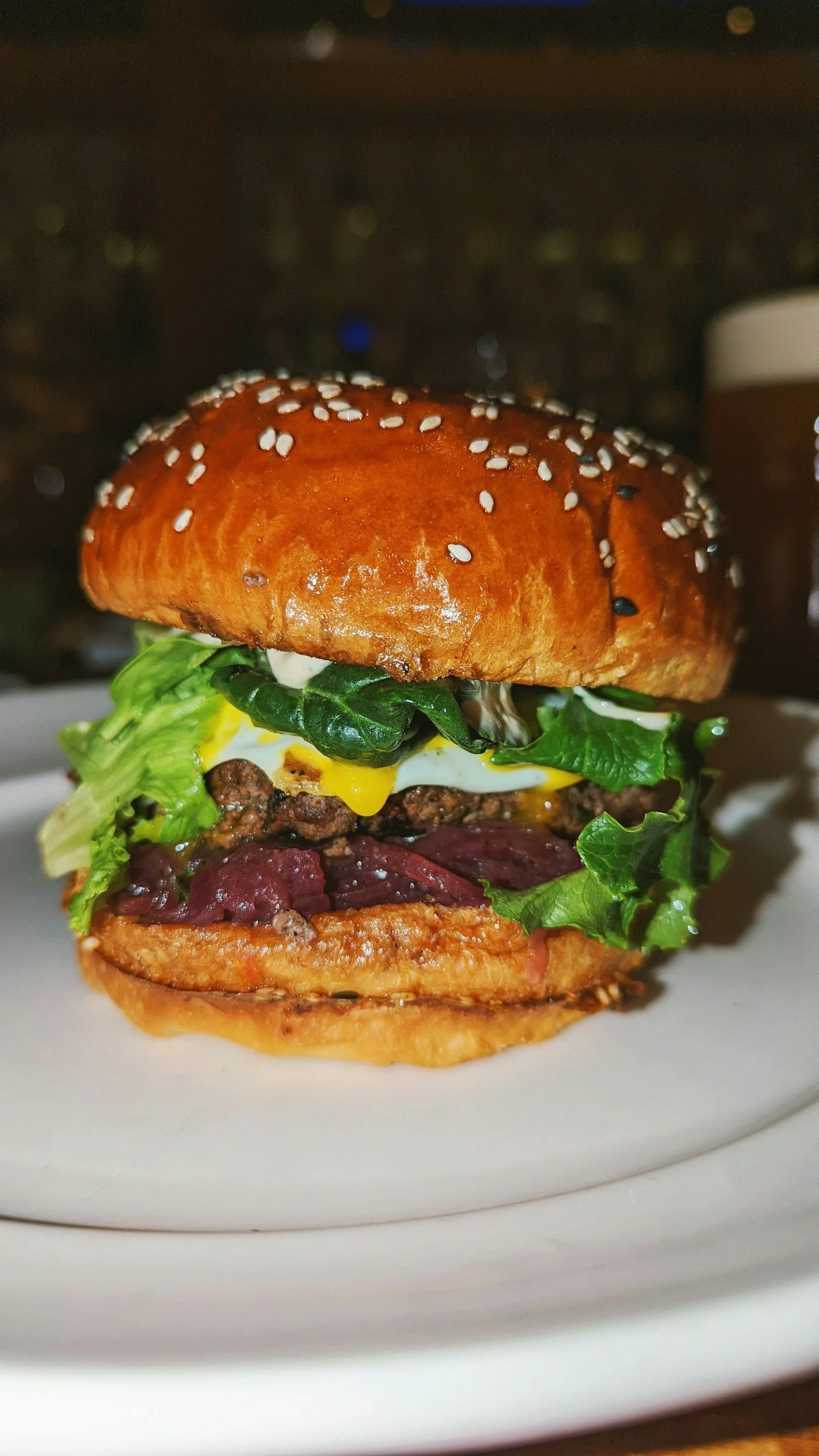 A close-up of a gourmet burger with lettuce, cheese, and beef patty on a white plate.
