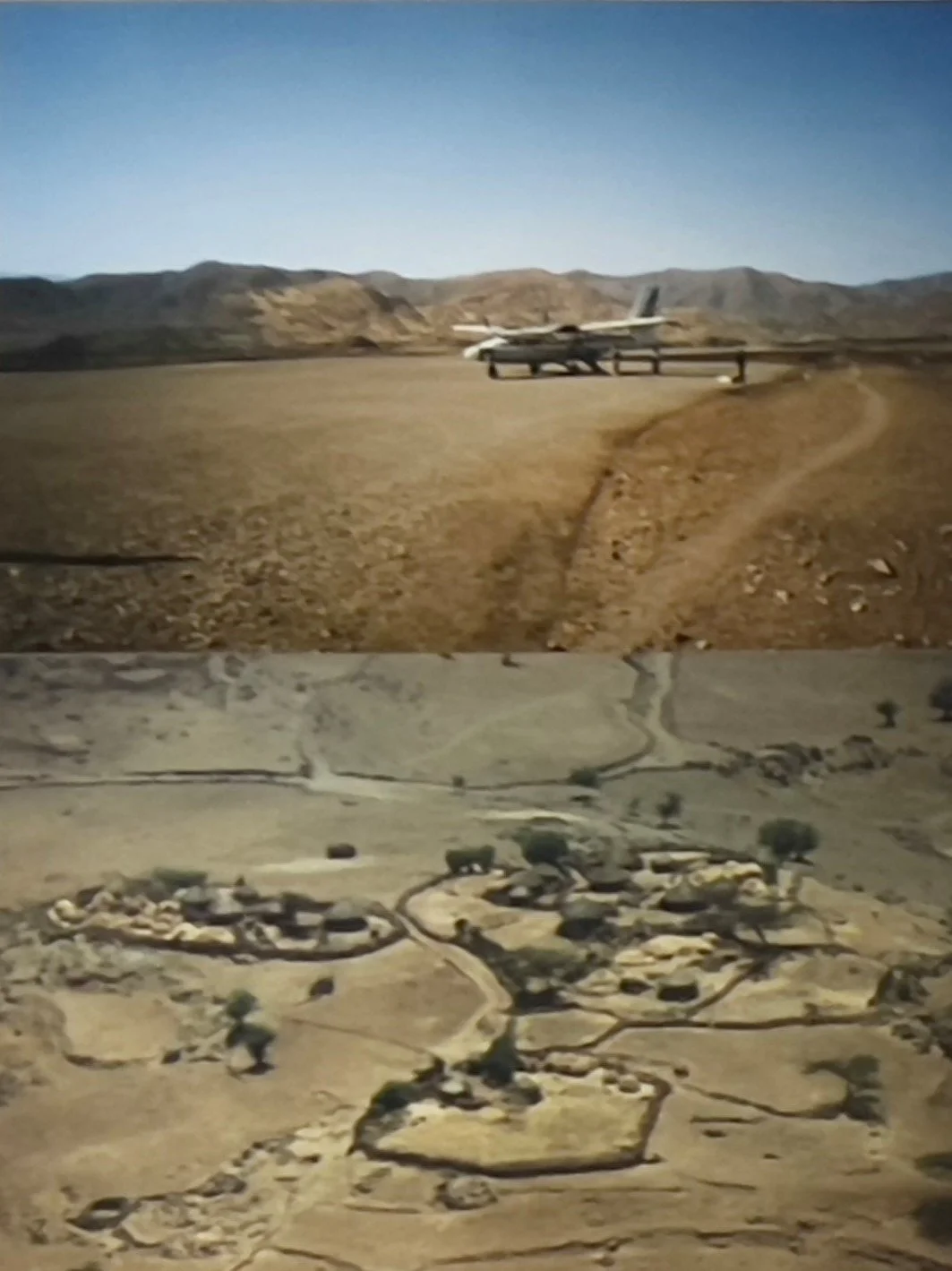 A photograph showcasing a desert landscape with an aircraft parked near a fence in the background and a model of a desert settlement in the foreground.