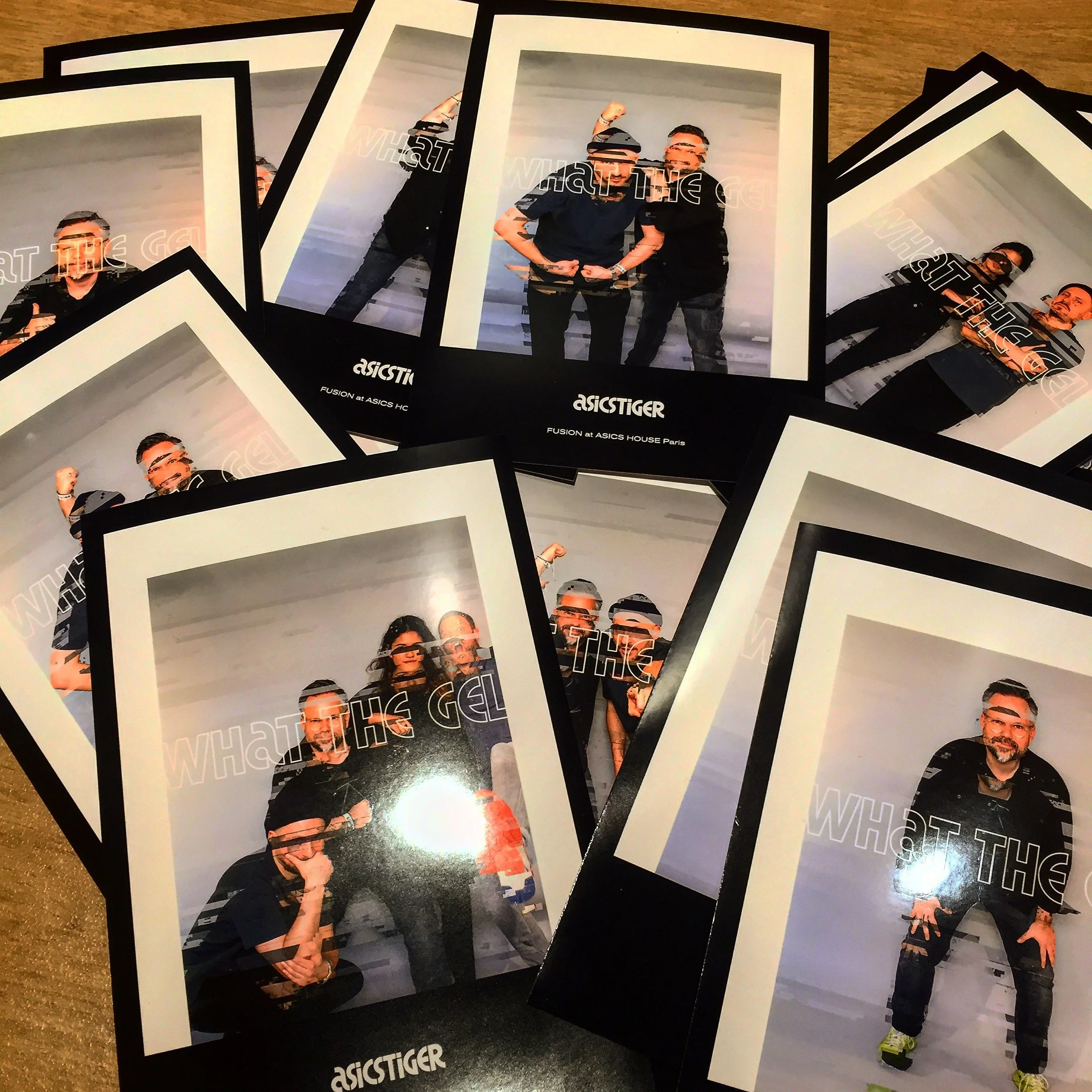 Mehrere Fotokarten, die eine Gruppe von Menschen in verschiedenen Posen zeigen, liegen auf einem Tisch. Die Karten haben weiße Rahmen und sind mit schwarzen Hintergründen gestaltet, mit Text, der 'Asics Tiger' und 'Fusion at ASICS House Paris' enthält.