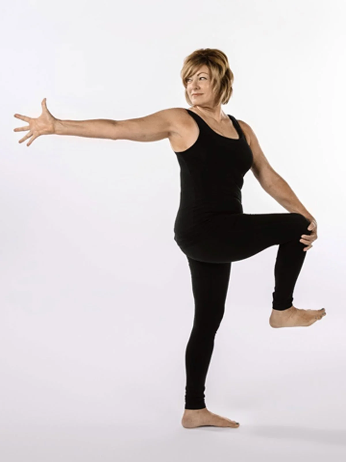 A woman in black yoga attire demonstrating a yoga pose against a plain white background.