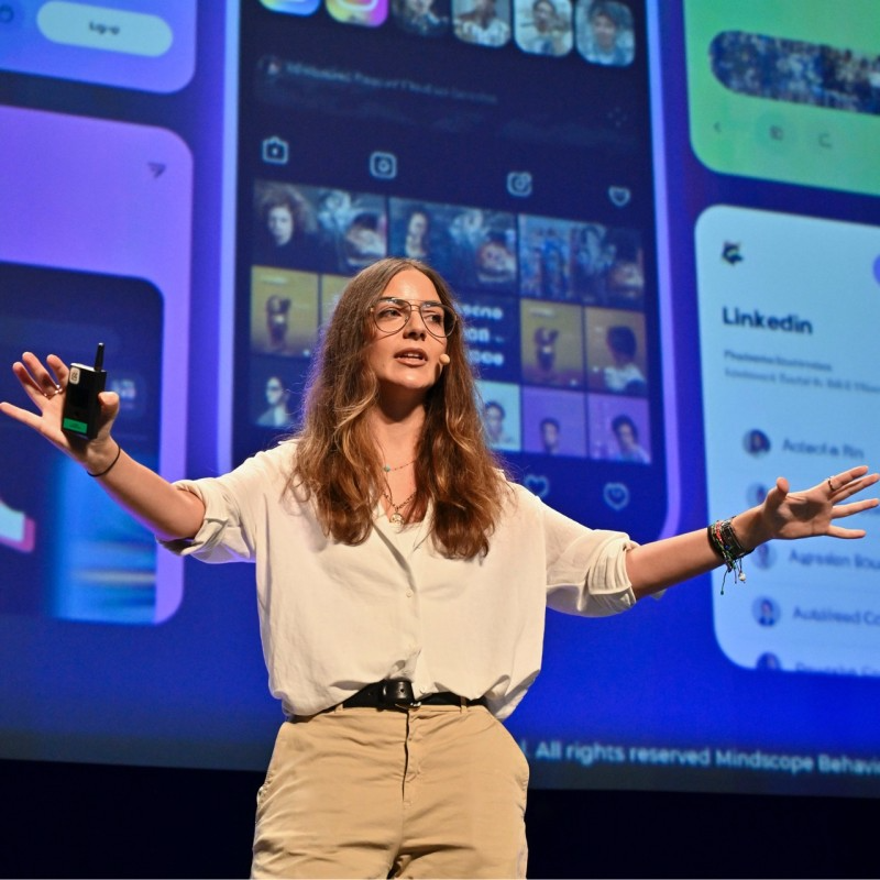 Lea Karam on stage, with her arms open as she addresses an audience