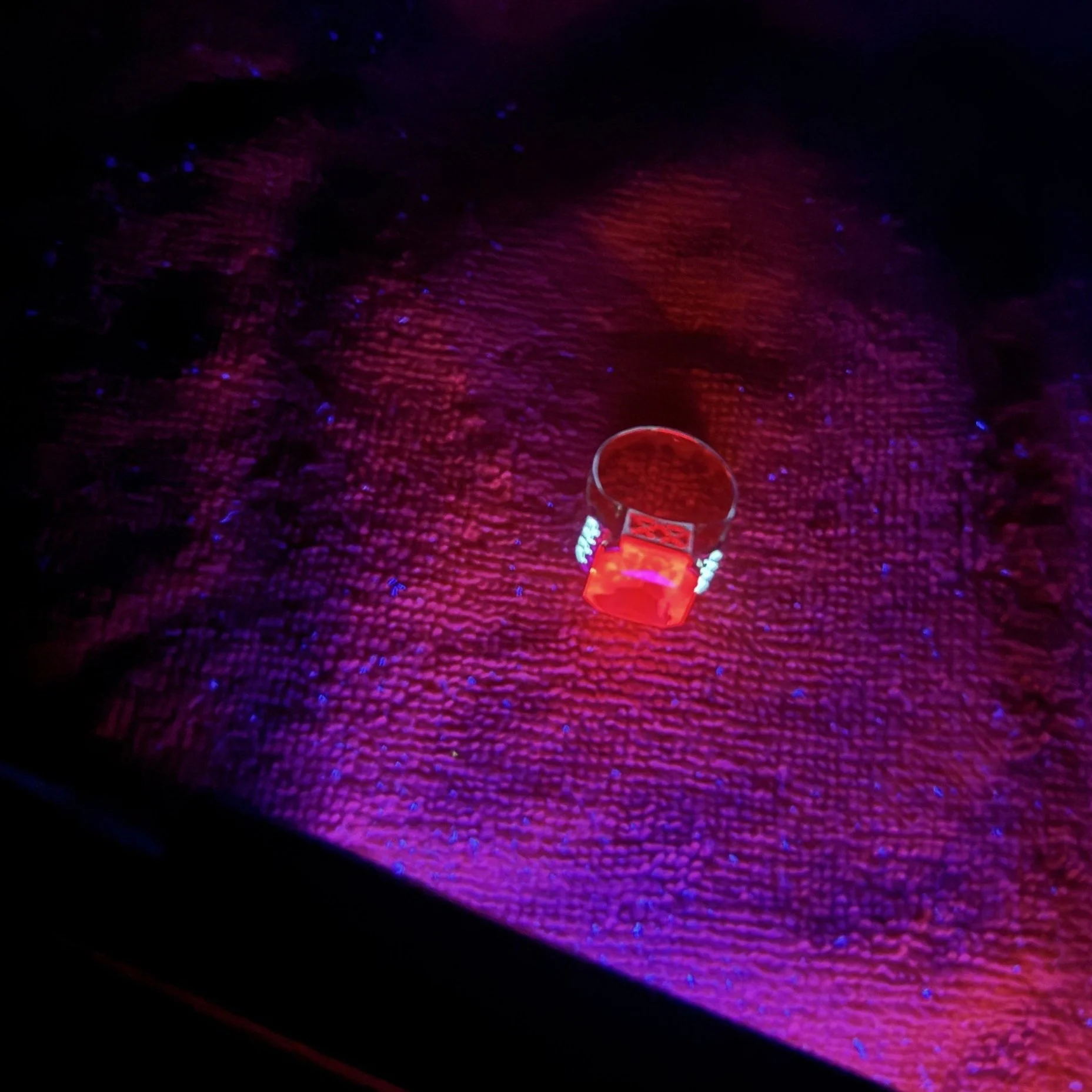 a synthetic ruby ring reacting to Longwave UV light and real diamonds also reacting to LWUV light