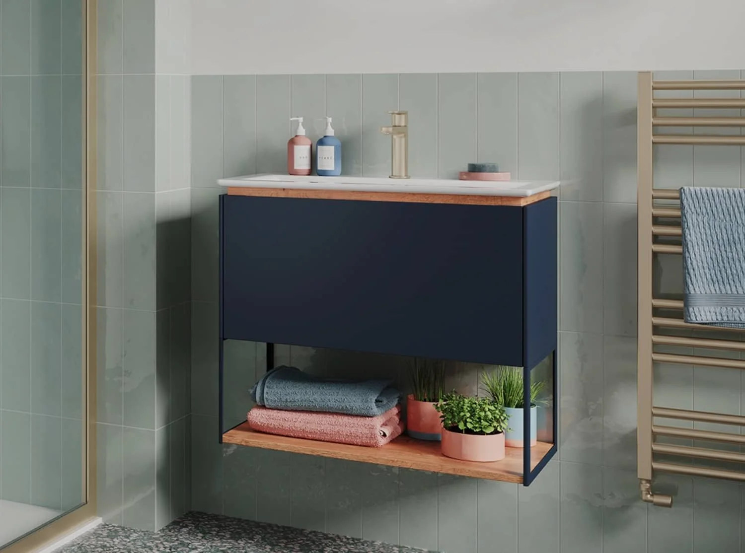 A modern bathroom vanity with a blue cabinet, a white countertop, and a gold faucet, with two potted plants and folded towels underneath, and a towel rack with a blue towel beside it.