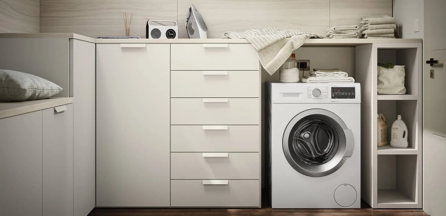 A washing machine in a laundry room with stacked towels, detergent bottles, and shelves for storage.