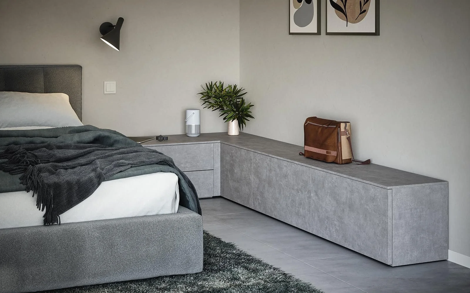 A modern bedroom with a grey upholstered bed, dark blanket, bedside table with a plant, a white humidifier, and a leather bag on a long grey cabinet, with wall art above.