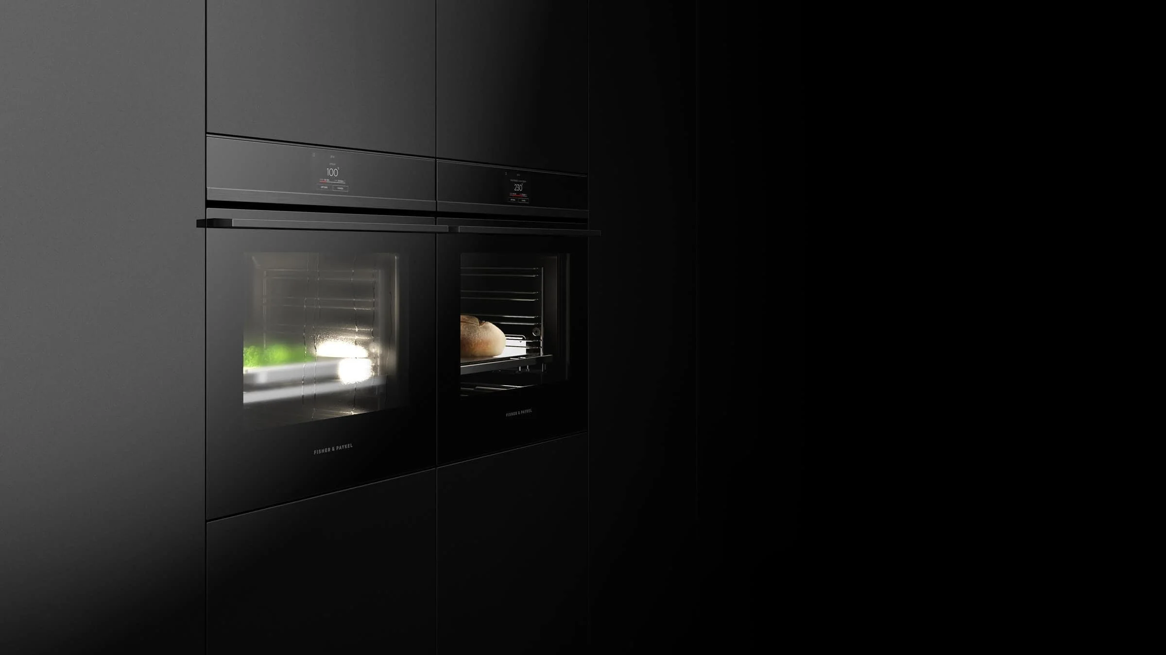 Fisher & Paykel. A modern kitchen with black cabinetry and built-in ovens, one of which has a loaf of bread inside.