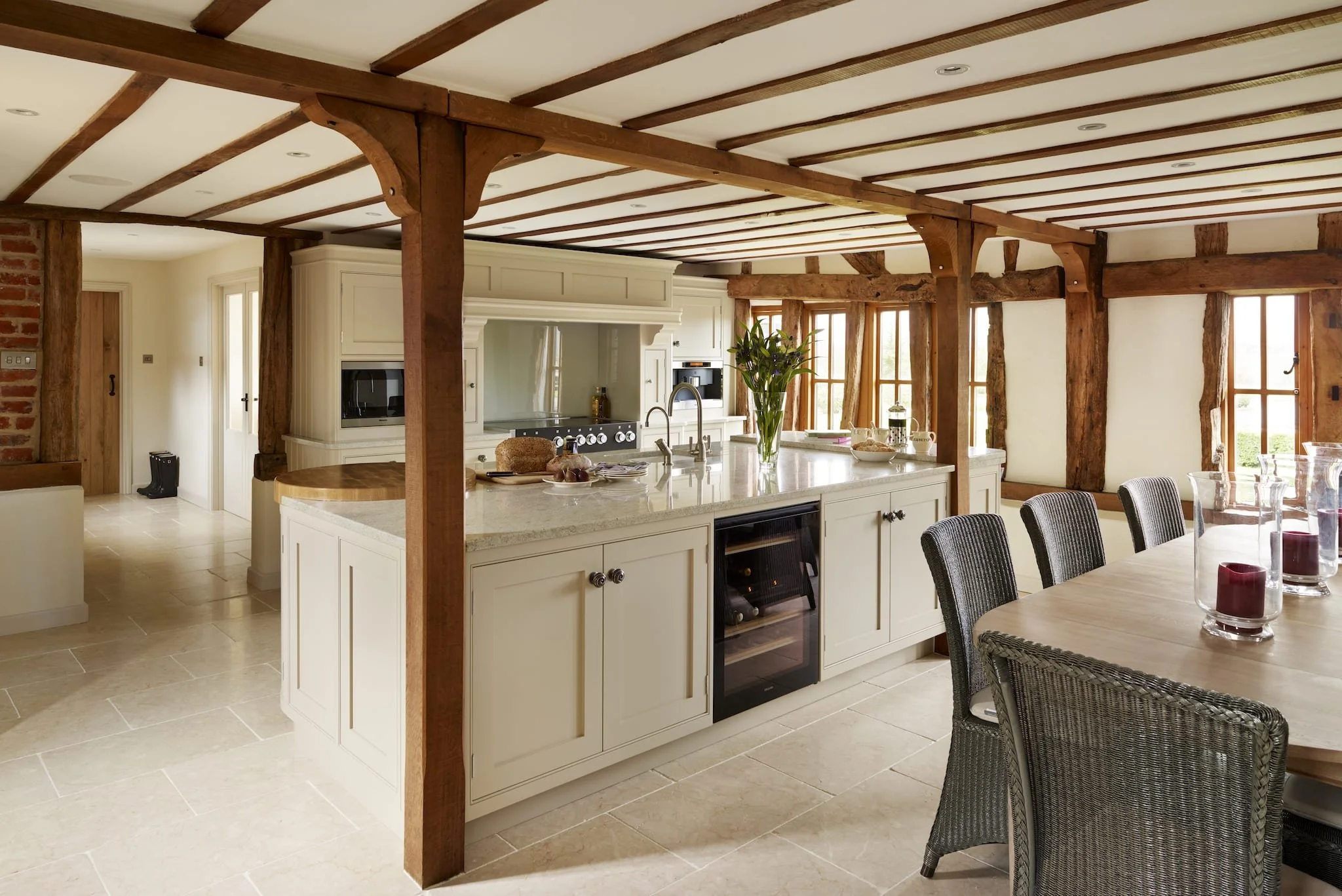 Spacious kitchen with wooden beams, white cabinets, a large island, and a wooden dining table with chairs.