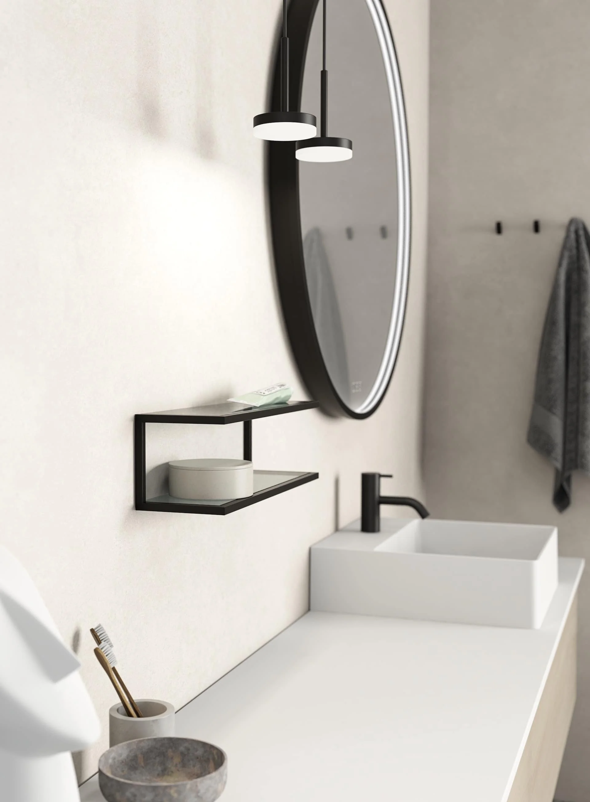 Modern bathroom with oval mirror, black and white accents, wall-mounted shelf with small container, white sink, black faucet, hanging towels, toothbrush holder with toothbrushes.
