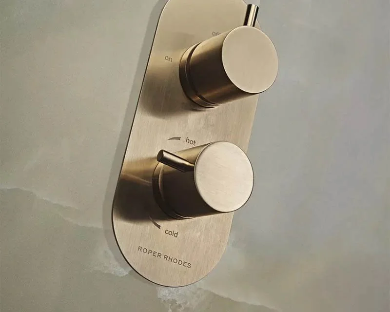 Silver shower water control panel with two knobs, one for temperature and one for water flow, labeled 'hot' and 'cold', by Roper Rhodes.