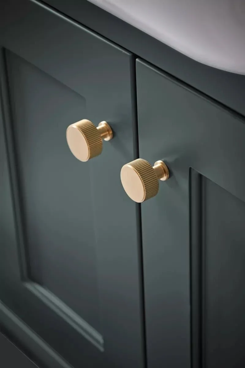 Close-up of dark blue cabinet with two gold round knobs.