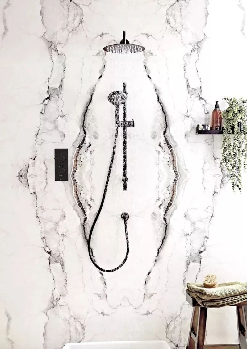 Rustic shower wall art depicting a black silhouette of a showerhead, hose, and faucet on a cracked marble-style background.