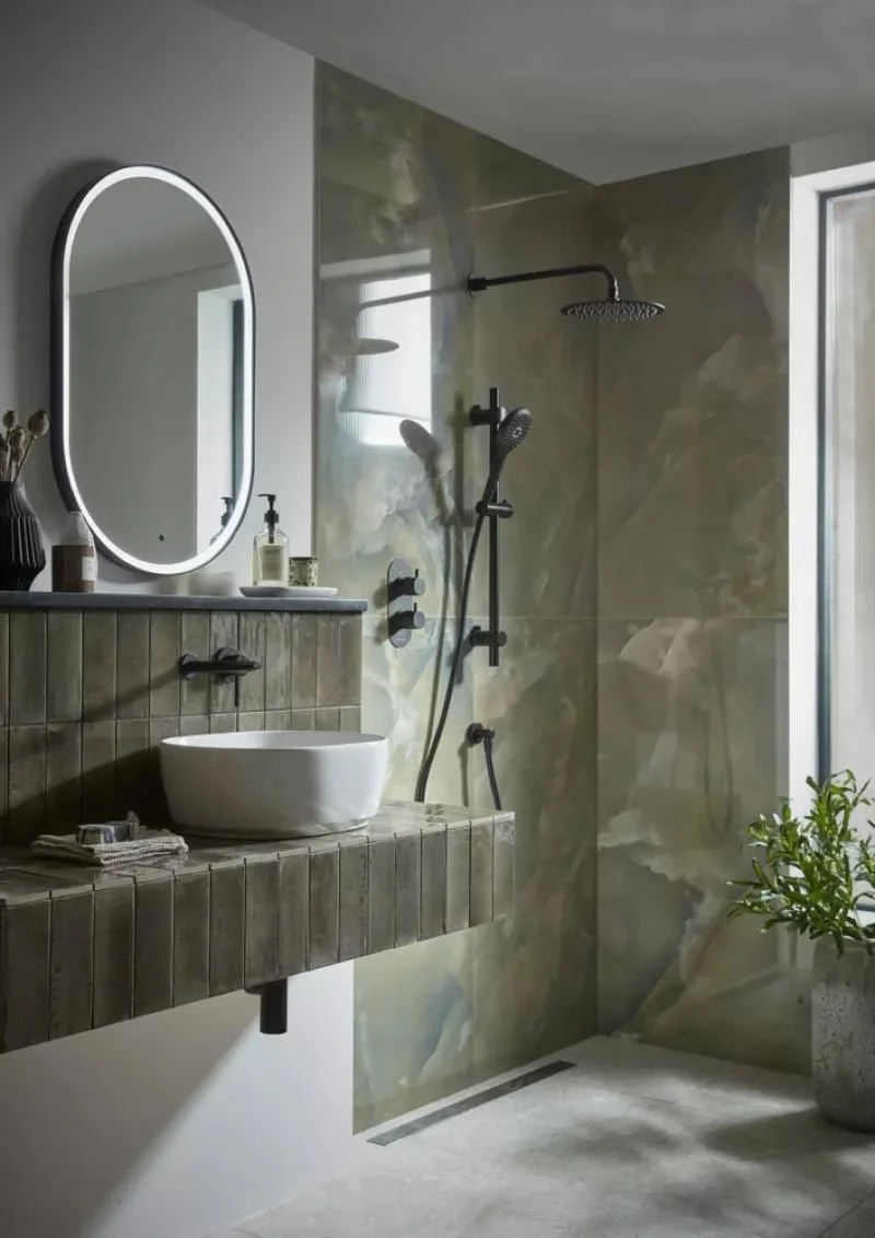Modern bathroom with a round mirror, vessel sink on a tiled vanity, and a walk-in shower with a rainfall shower head and a handheld shower fixture.
