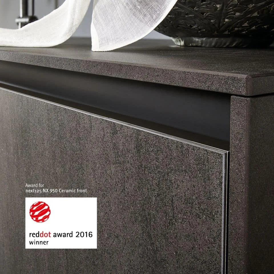 Close-up of a modern cabinet or sideboard with textured dark surface and a label indicating a red dot award from 2016.