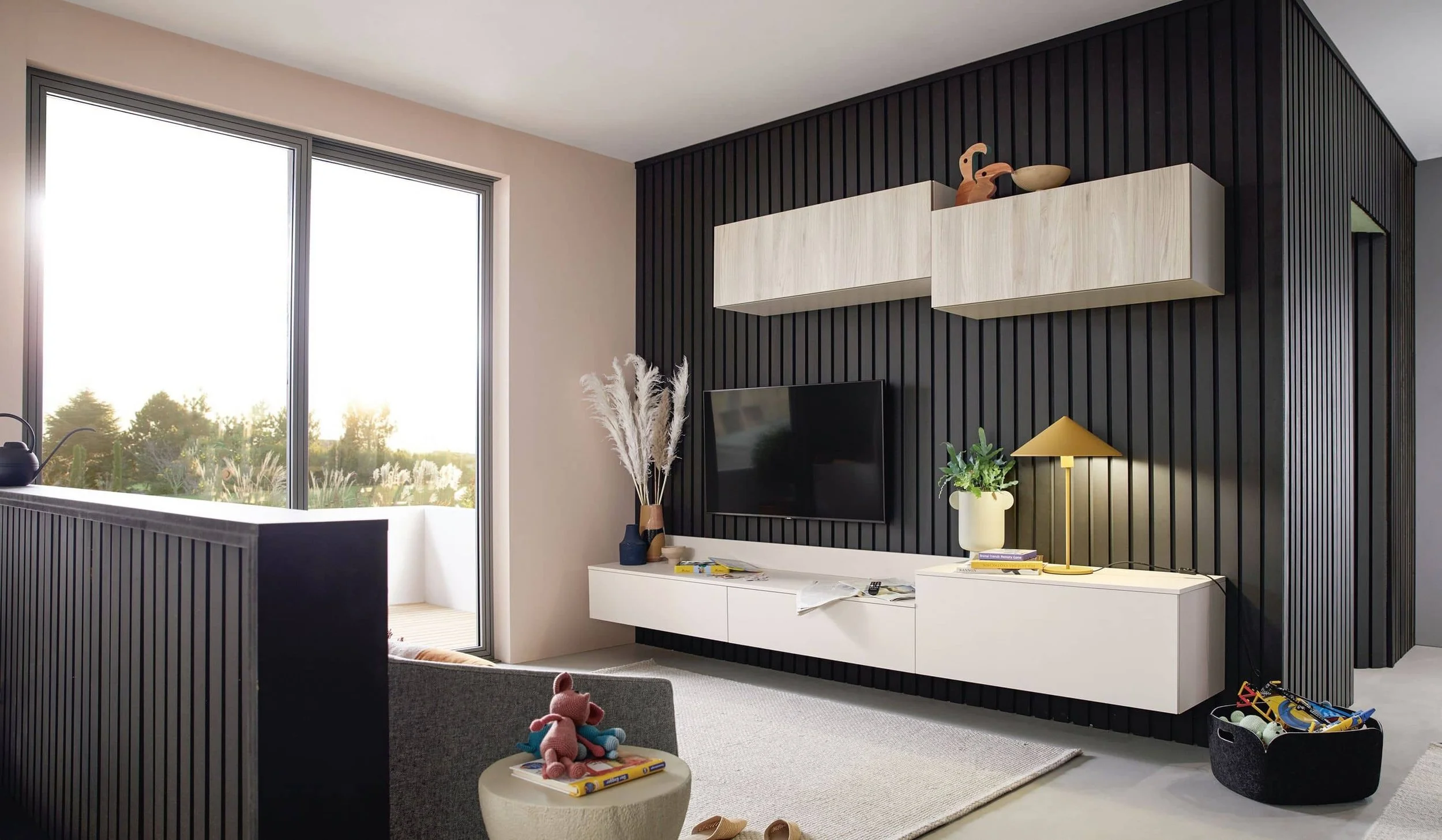 Modern living room with large glass sliding door, black accent wall with floating shelves, white TV console, TV, decorative plants, and children's toys.
