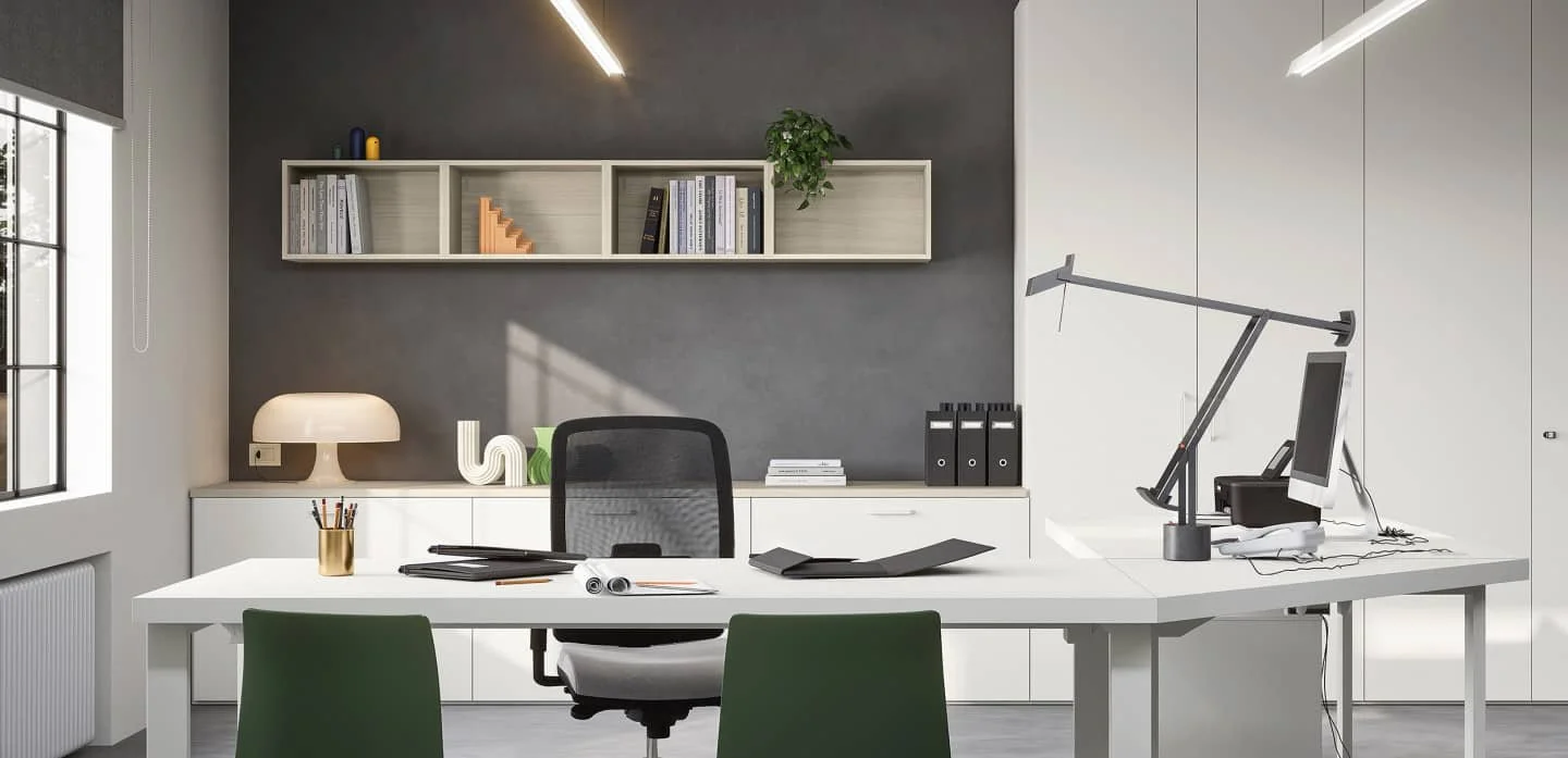 Modern office with white desk, black and green chairs, grey and white wall, shelves with books, a computer, desk lamp, desk organiser, and a window with blinds.