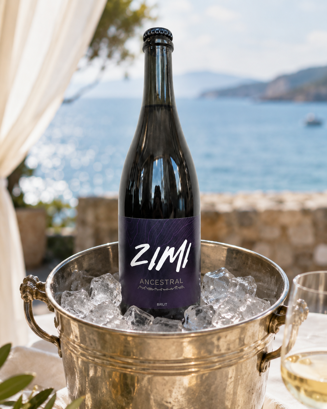 Botella de vino Zimi Ancestral en un cubo con hielo, frente a un paisaje de mar y montañas.