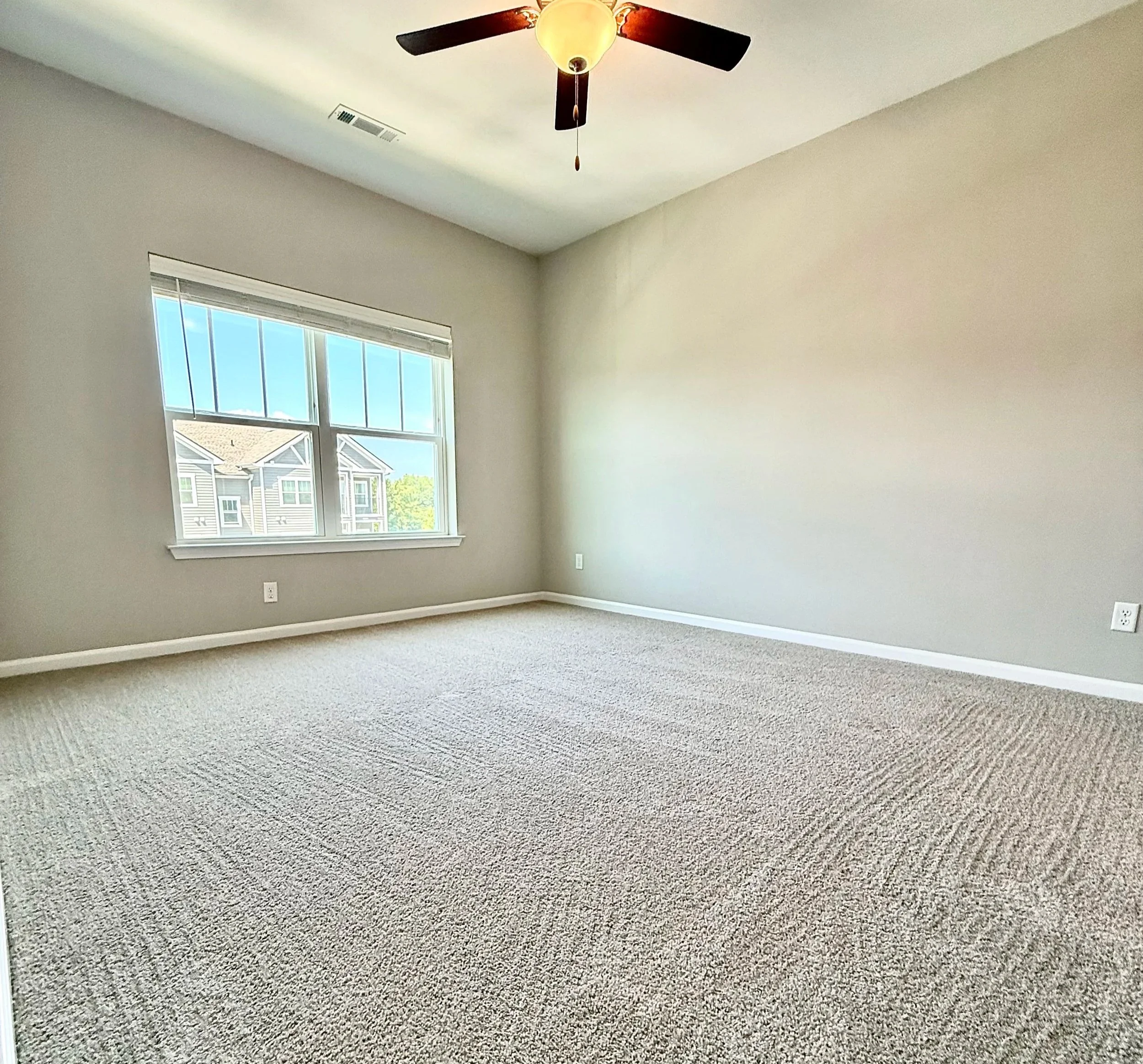 Bright, empty bedroom with freshly cleaned windows and deep cleaned carpet, ready for new residents.