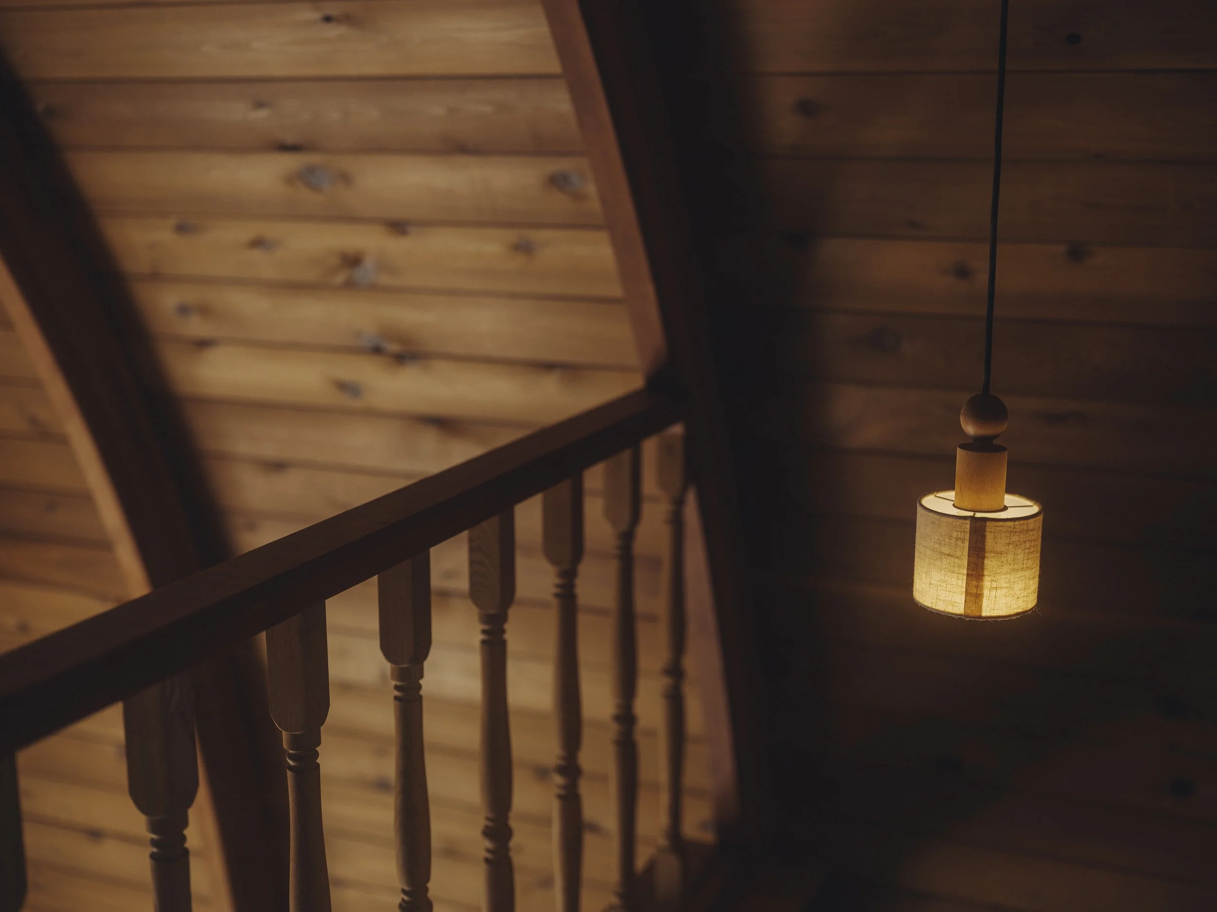 木製の壁と手すり、暖かい光を放つ吊り下げ式の照明.