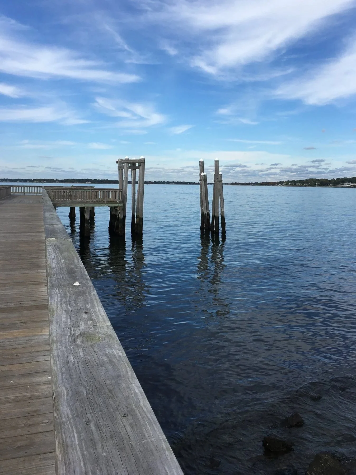 Wooden pier overlooking calm blue water under a bright sky