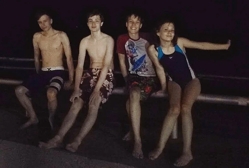 Author Krista Allen's four children pose together on a boat or dock at night.
