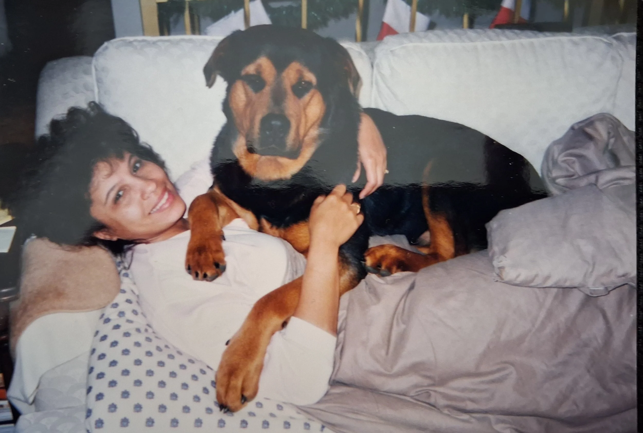 black-and-tan dog stretched out comfortably on a woman reclining on a couch