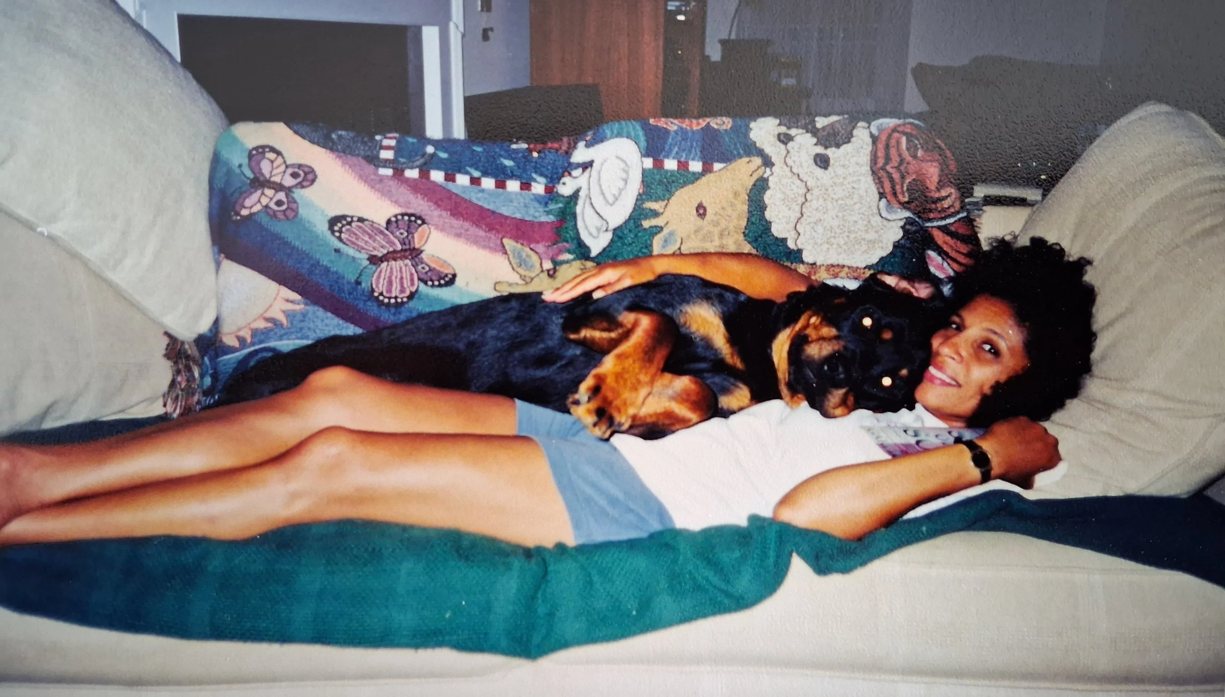 large black-and-tan dog resting beside a woman lying on a bed