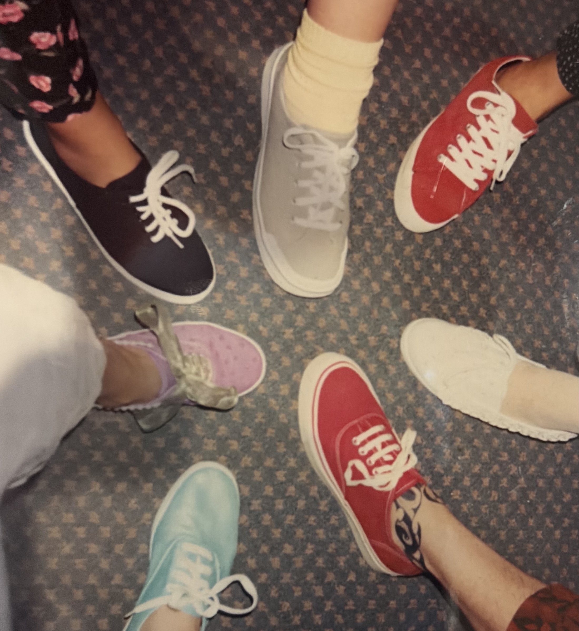Several people stand together, showing a variety of colorful casual shoes, including black, white, red, pink, and blue sneakers.