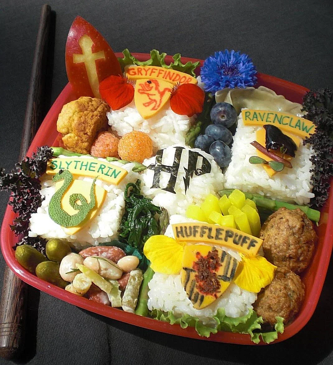 Colorful bento box arranged with rice and food shaped into the four Hogwarts house crests.
