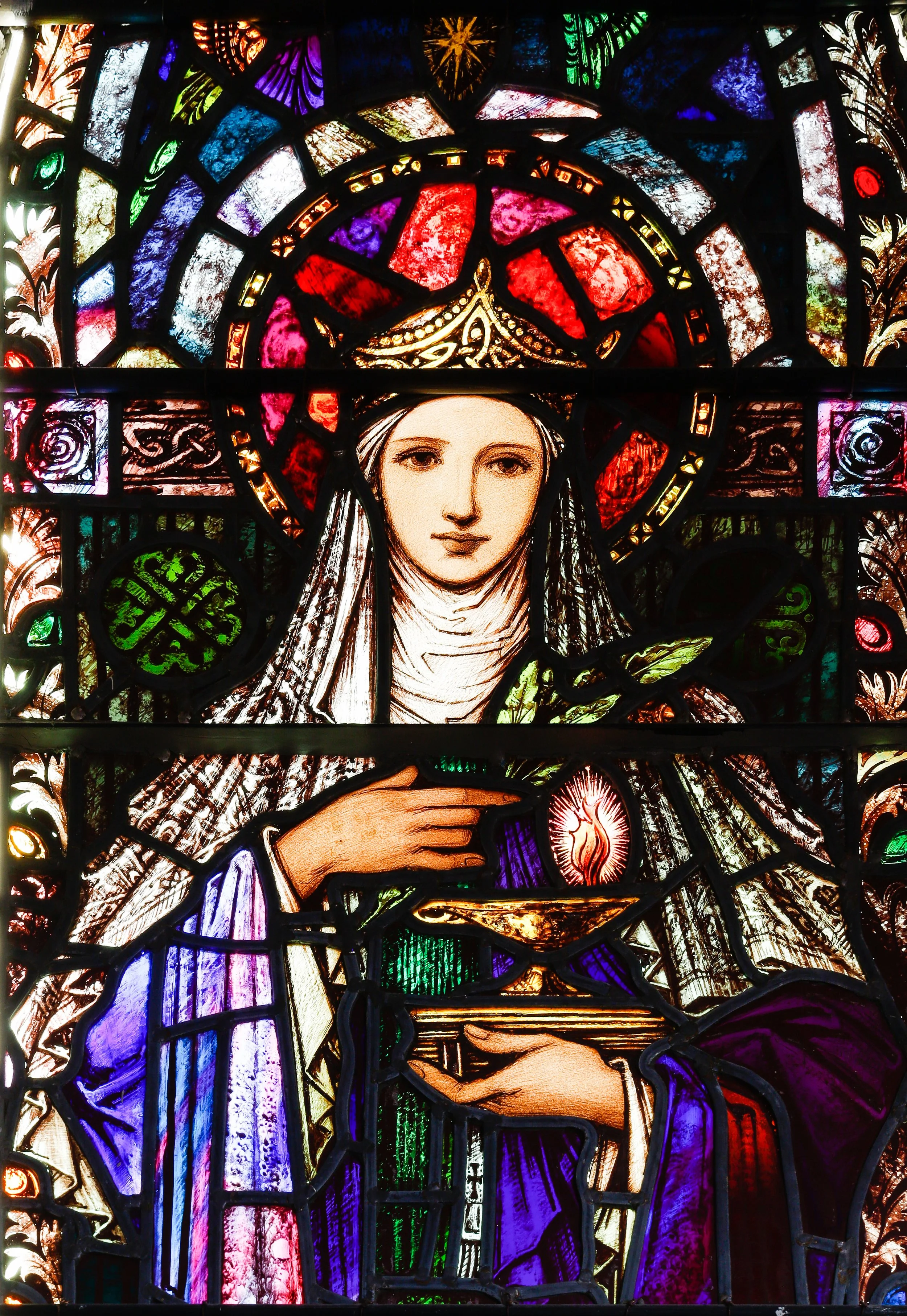 Stained glass artwork depicting Saint Brigid with rich colors and light filtering through.