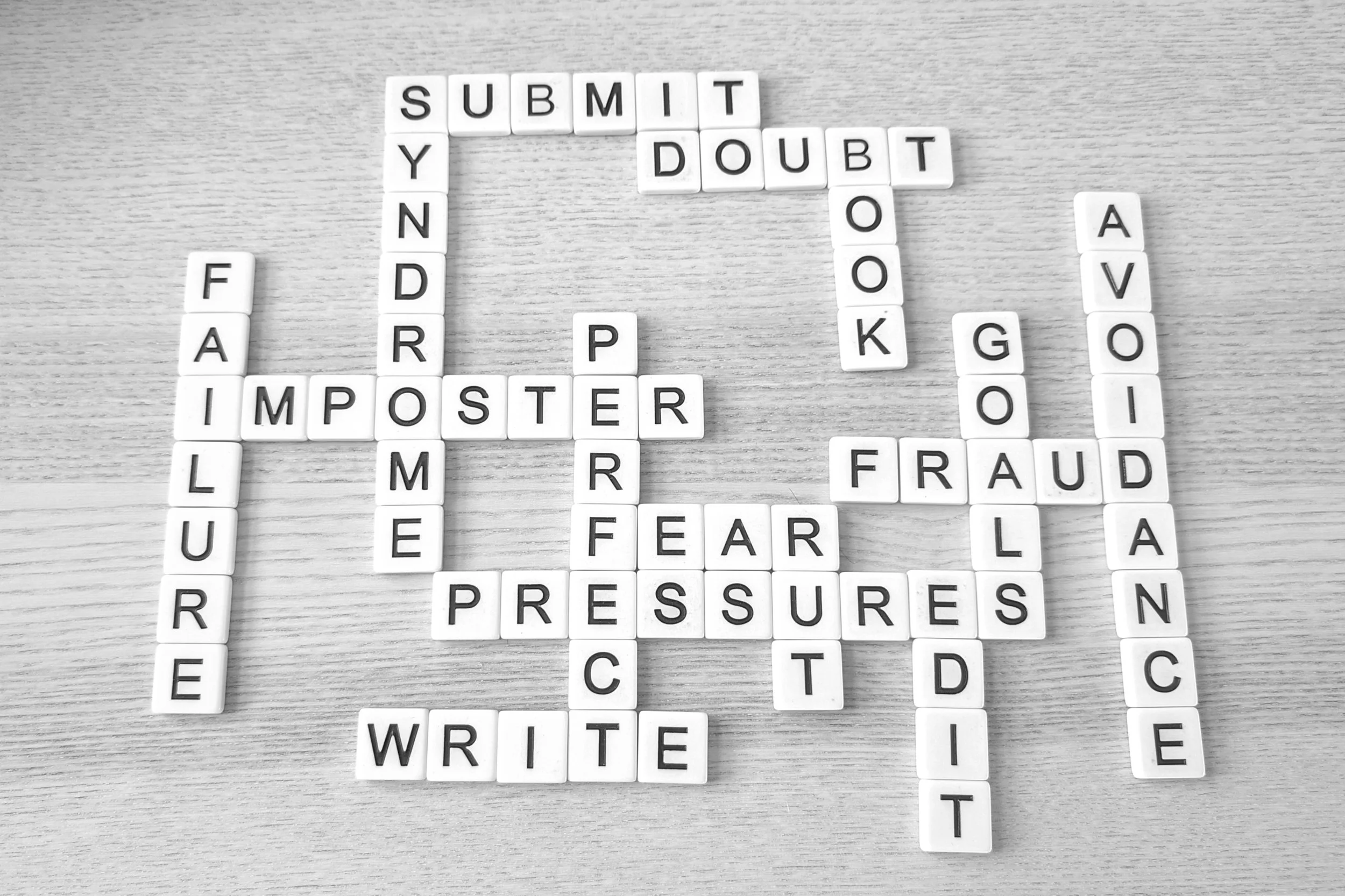 Black-and-white photo of letter tiles spelling words about writing, doubt, and rejection