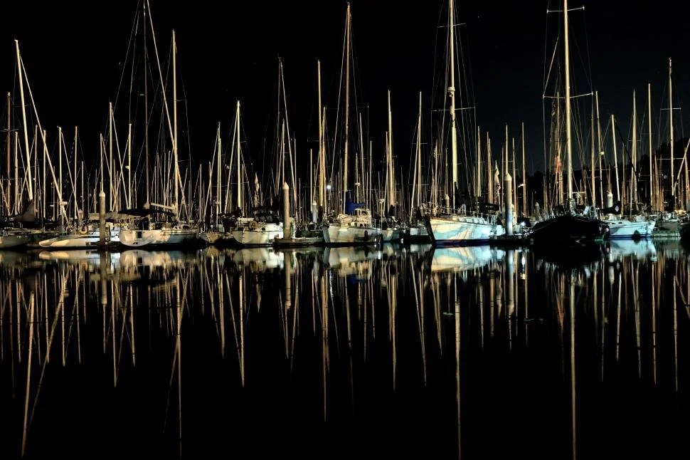 nighttime harbor with boats and their reflections in water