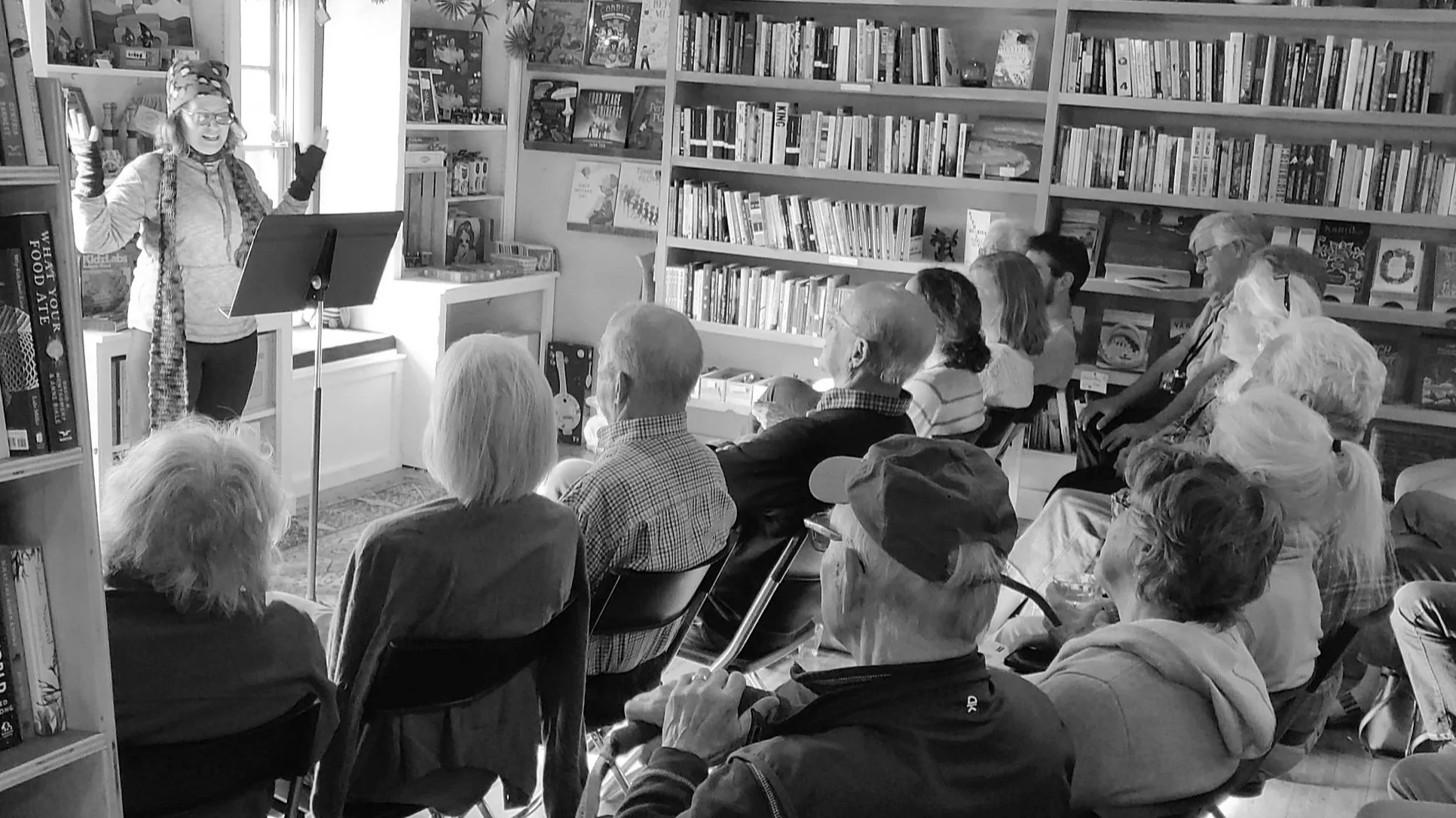Black-and-white photo of a writer reading to an audience gathered in Davoll's store