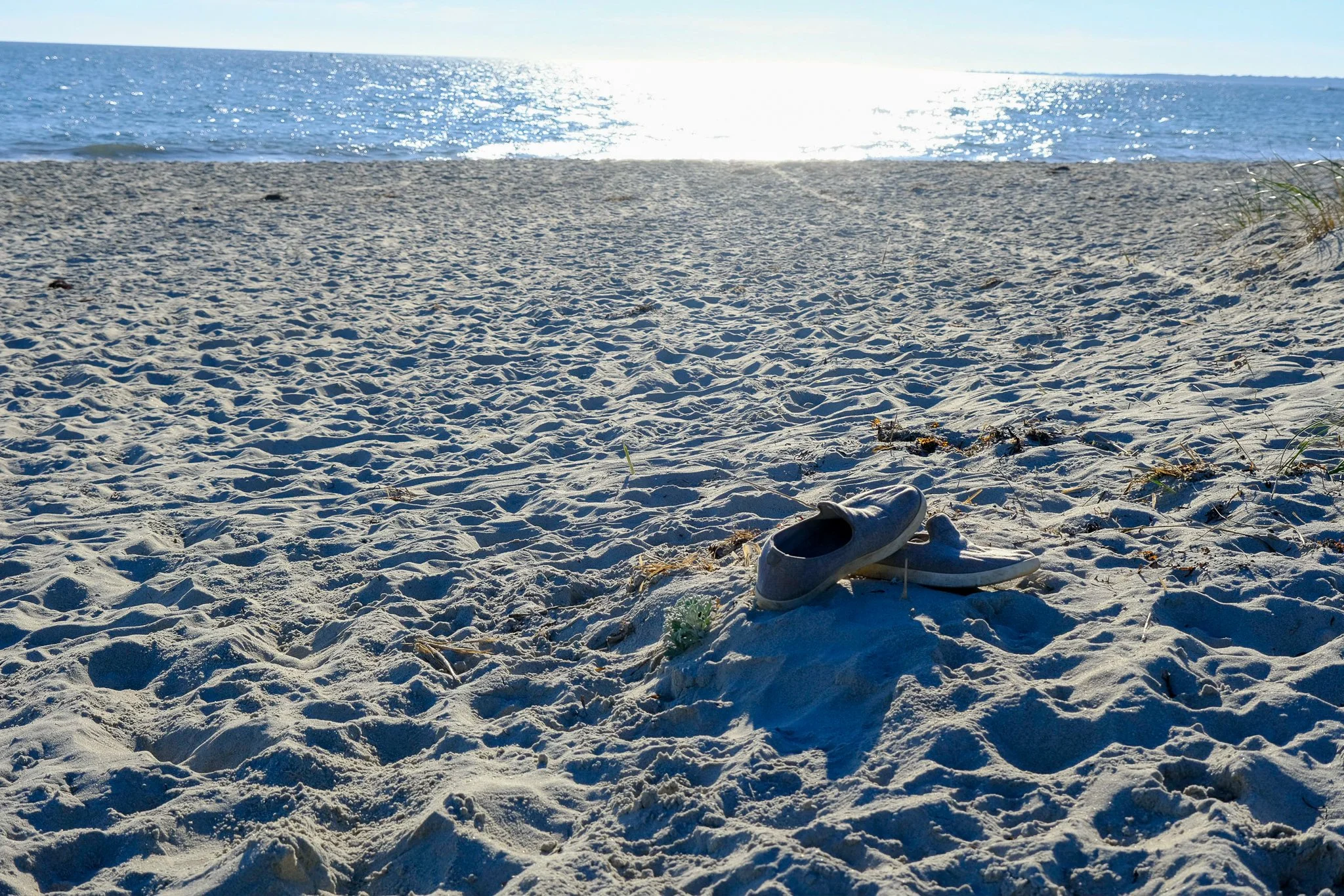 sunny sandy beach with two empty sneakers at the forefront