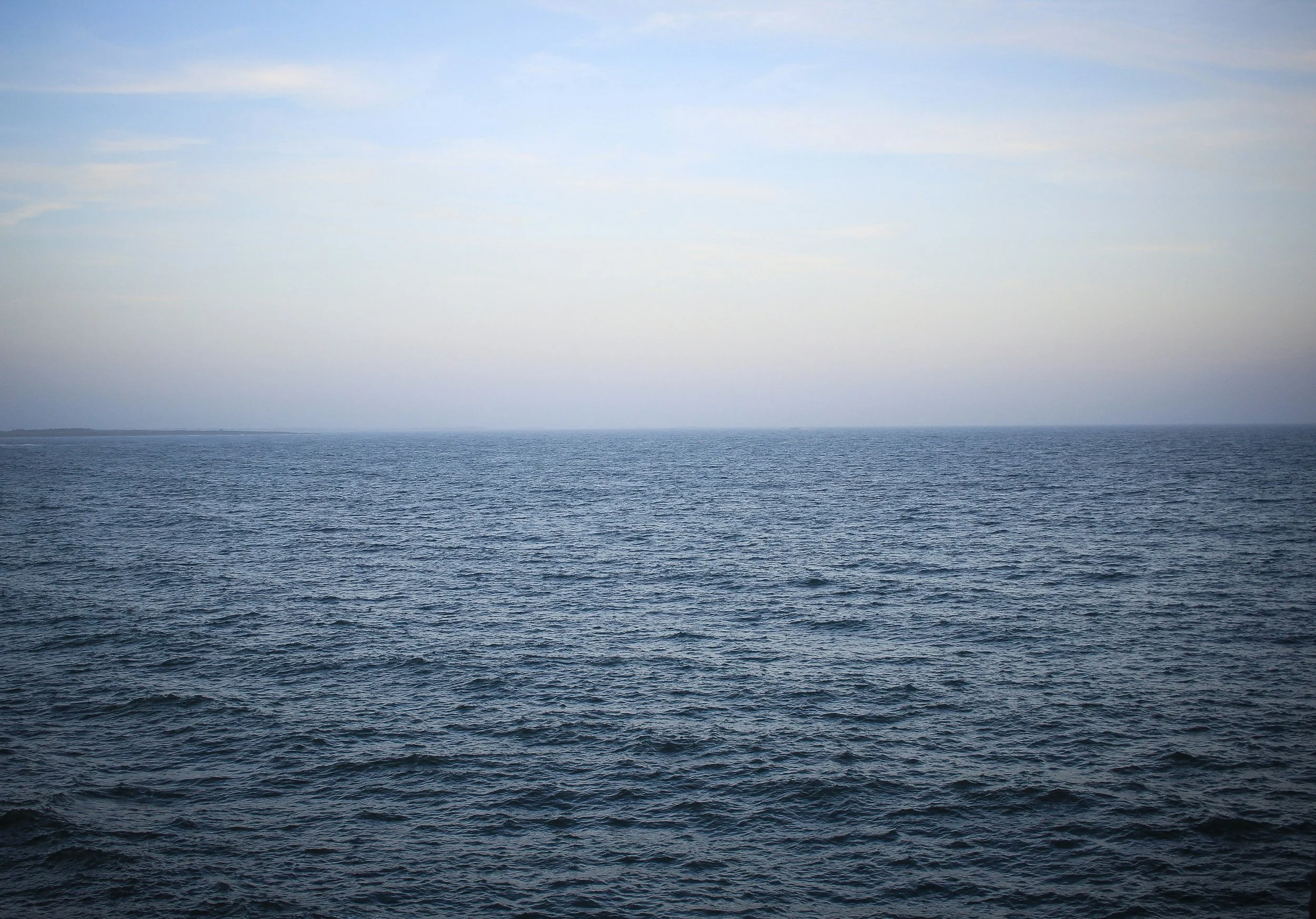 Calm open sea water stretching to the horizon beneath a clear sky