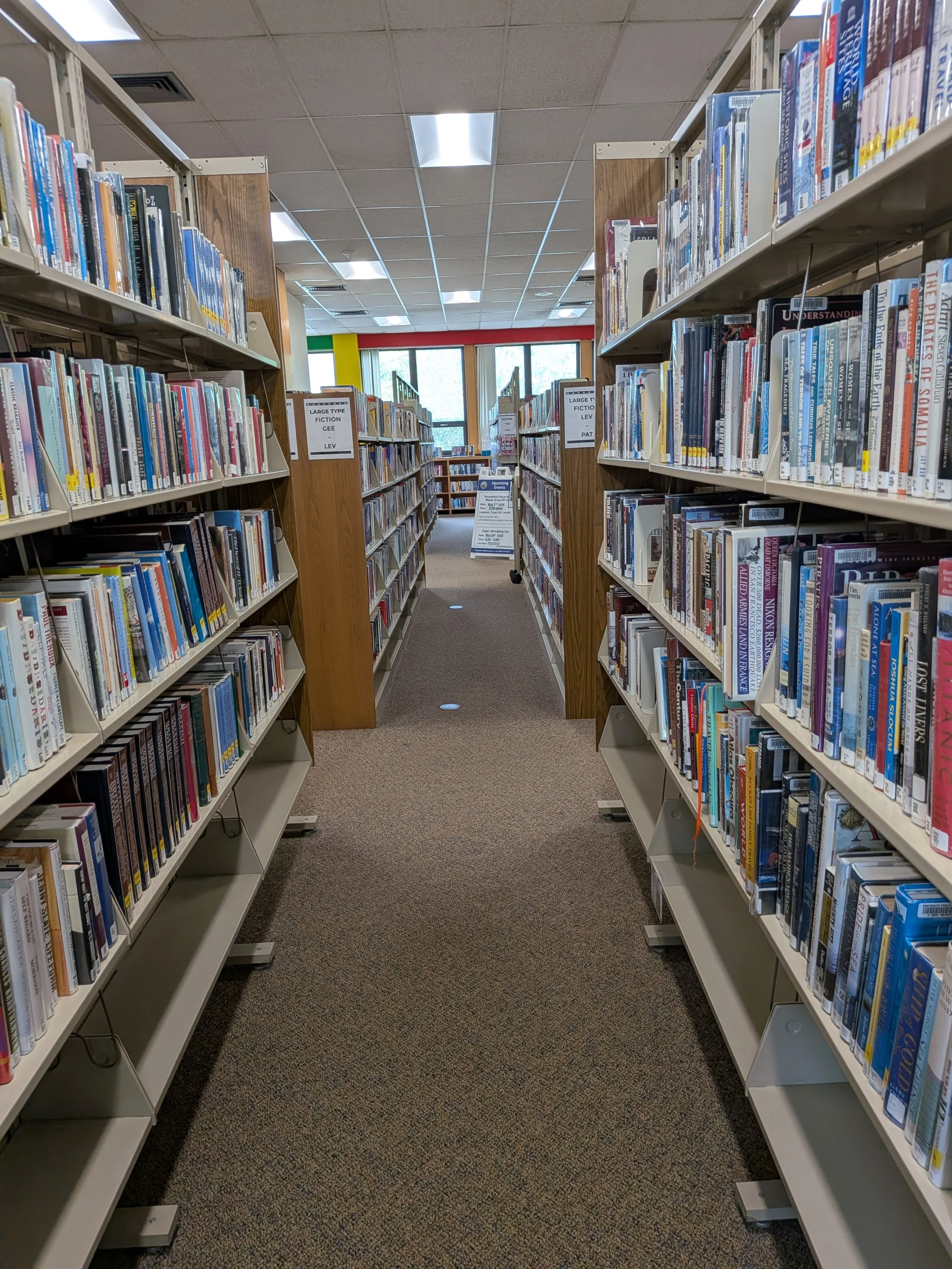 Rows of library bookshelves filled with books in a library aisle.