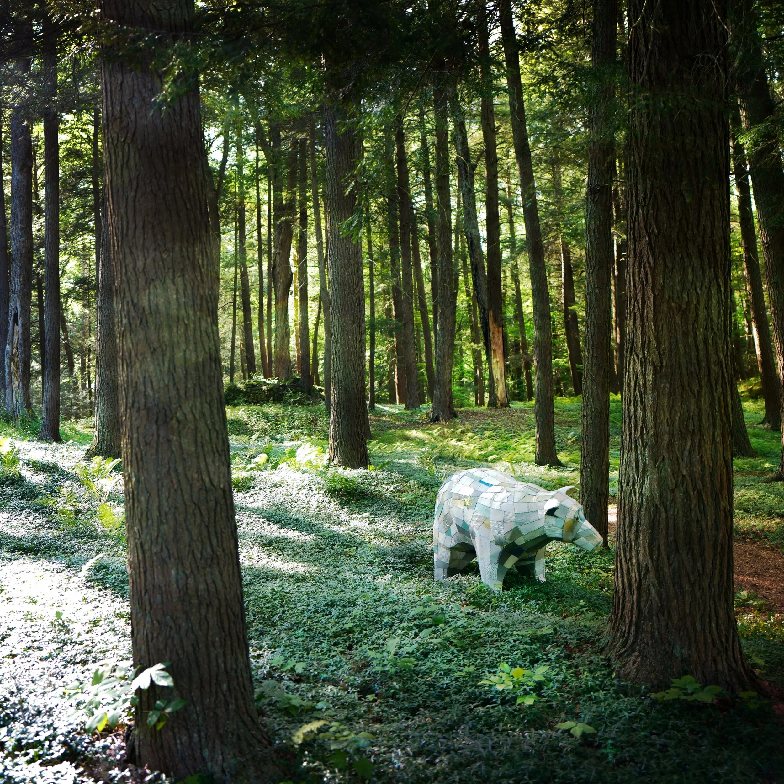 a sculpture of a polar bear in colorful white tiles in a green forest