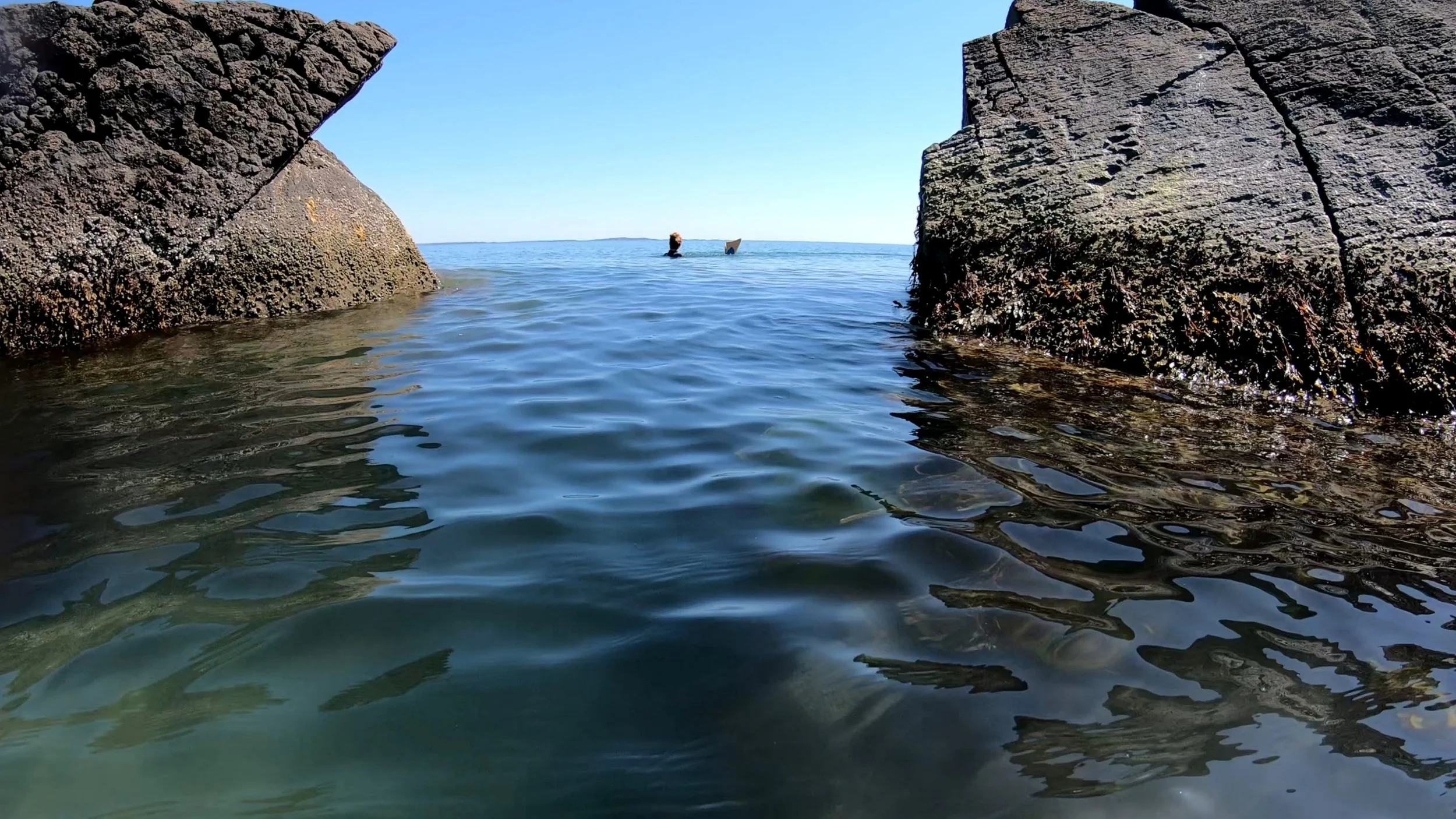 Krista Allen swimming in Buzzards Bay between two huge rocks