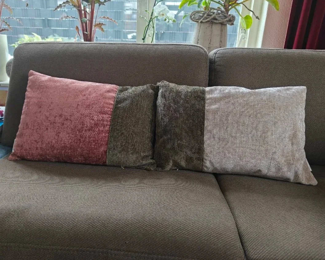 links een terracotta en donker groene sierkussen, rechts een donkergroene en beige sierkussen.