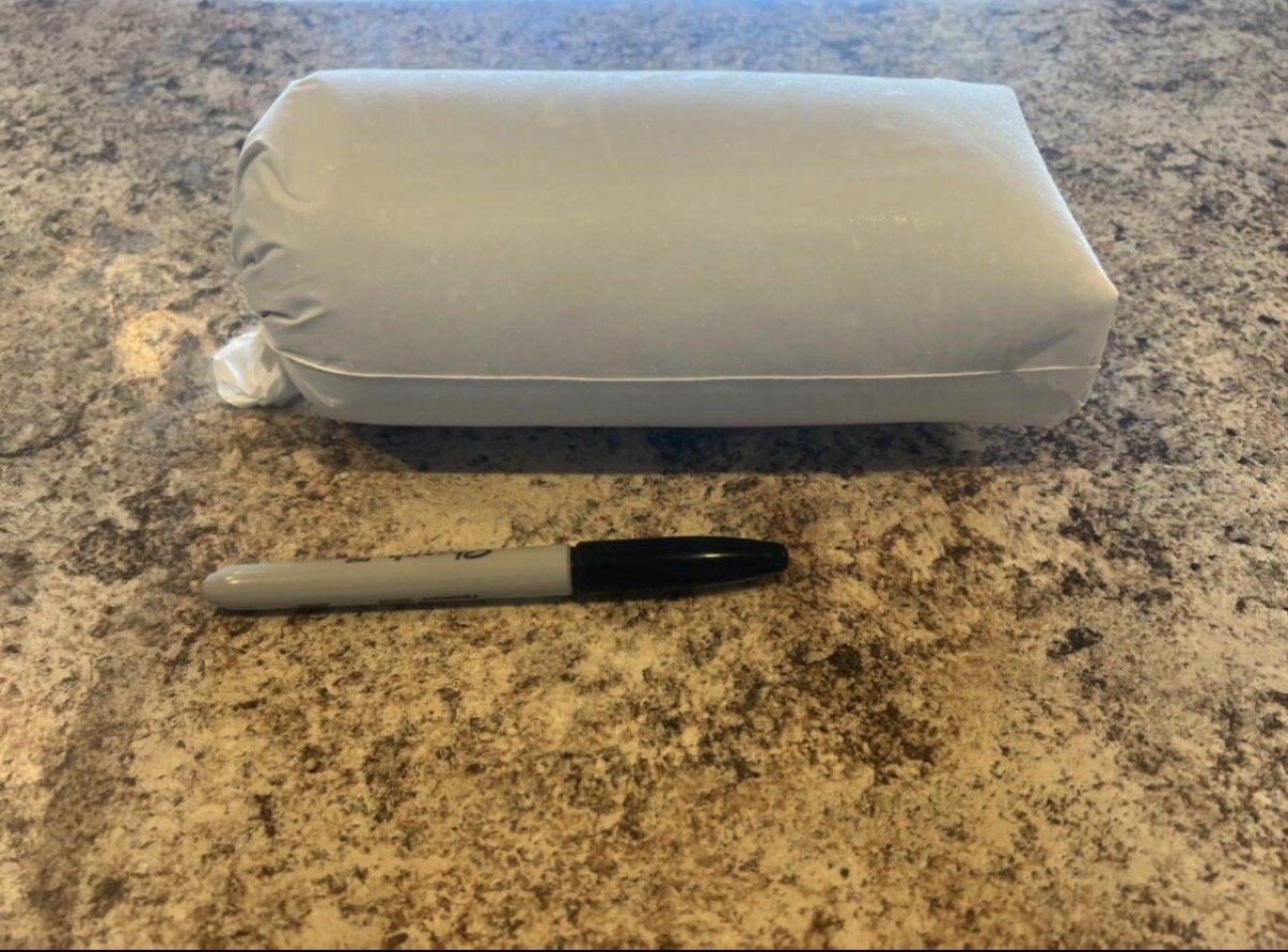 A rectangular package wrapped in white paper and a black and white marker pen placed on a speckled brown countertop.