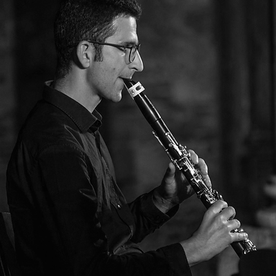 Uomo con occhiali che suona un clarinetto in bianco e nero.