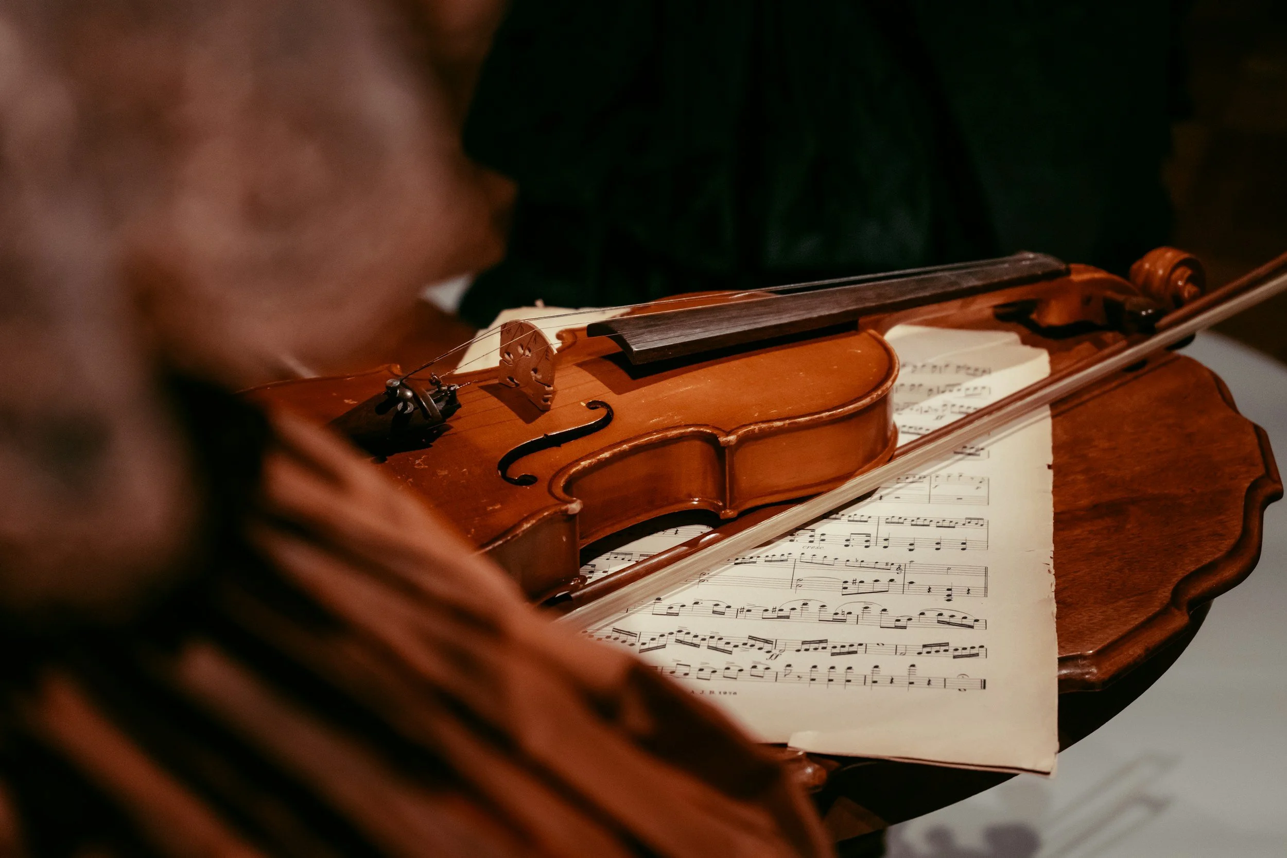Una persona che suona un violino con fogli di musica aperti davanti.