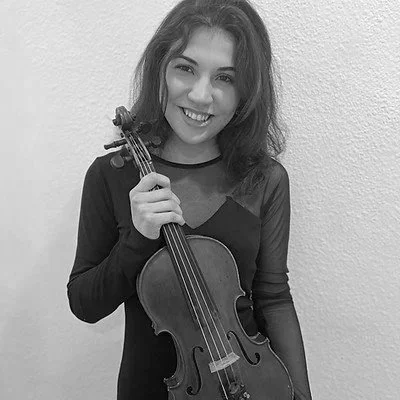 Una giovane donna con capelli castani che sorride, tiene un violino e un'asta.