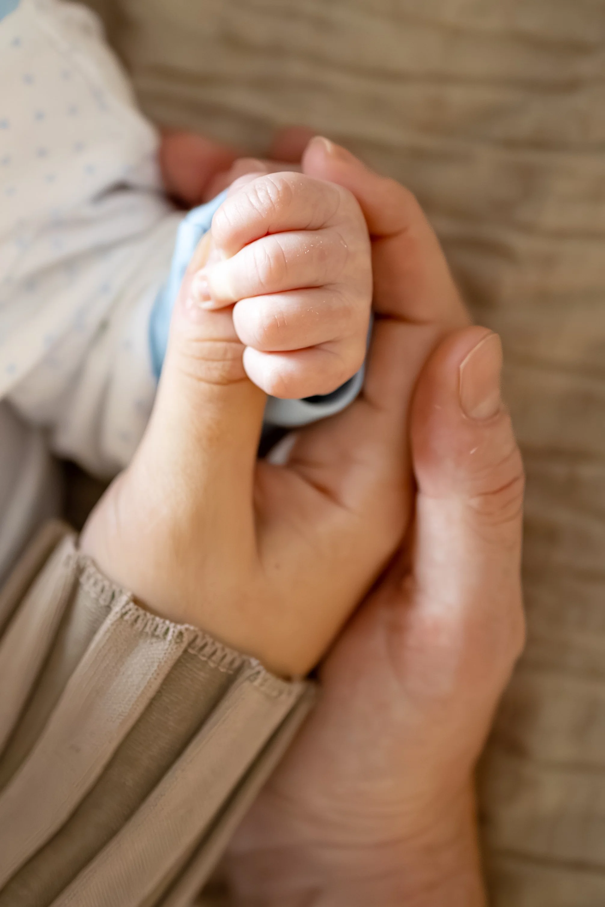 Close-up of an infant's hand clutching an adult's finger.