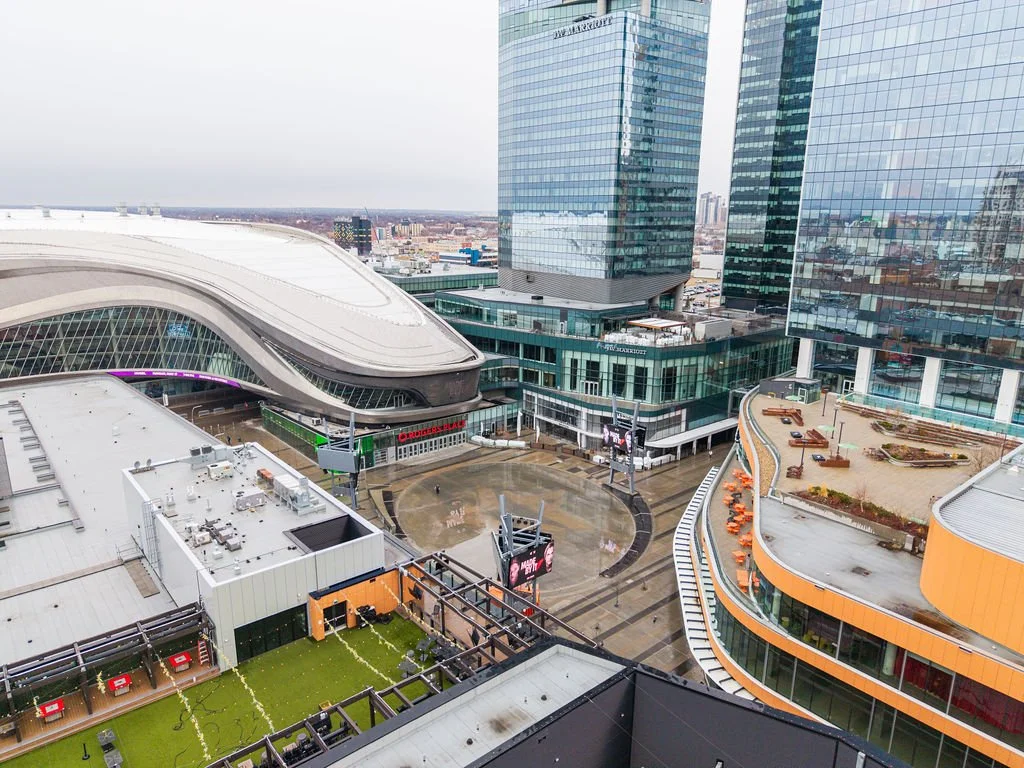 View of modern cityscape with skyscrapers, outdoor plaza, and wet ground.