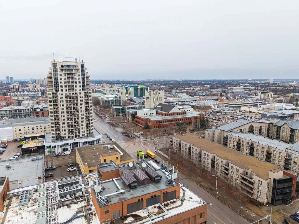 Cityscape with tall buildings, roads, and parking lots under an overcast sky