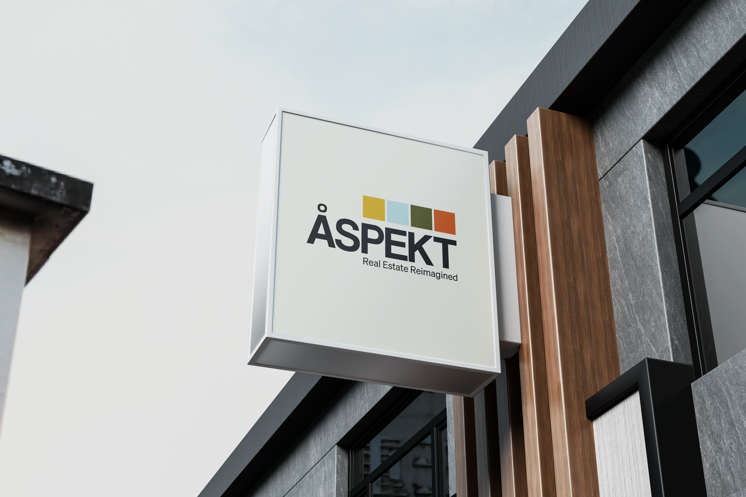 Exterior view of a modern building featuring a white sign with colorful squares and the text 'ÅSPEKT' and 'Real Estate Reimagined', along with wood and dark-colored architectural elements.