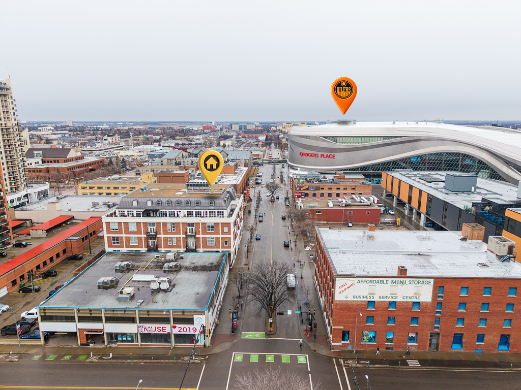 City street view with downtown buildings, residential and commercial structures, and a large arena labeled Rogers Place in the background. Icons indicating a house and Rogers logo are overlaid on the image.