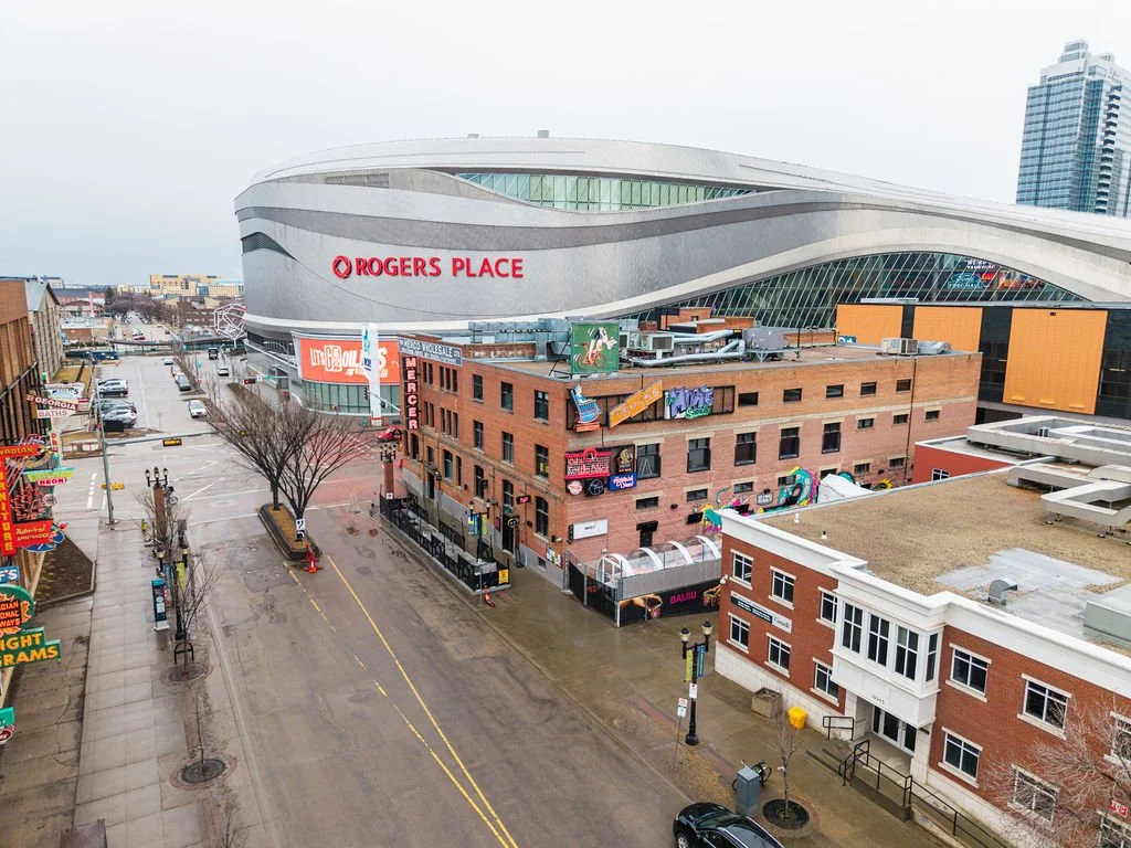 View of Rogers Place arena in Edmonton, Canada, with adjacent historic buildings and an empty street.