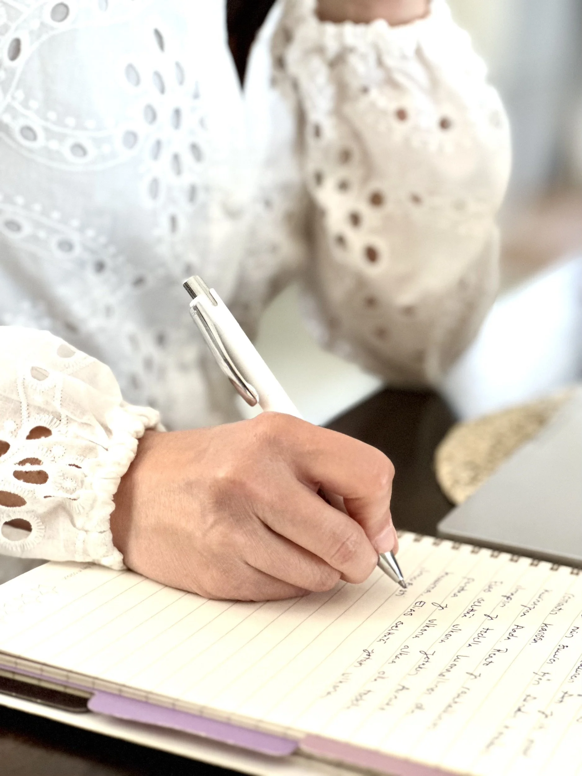 Yrittäjän käsi kirjoittaa brändikuvausasiakkaan tietoja muistikirjaan.